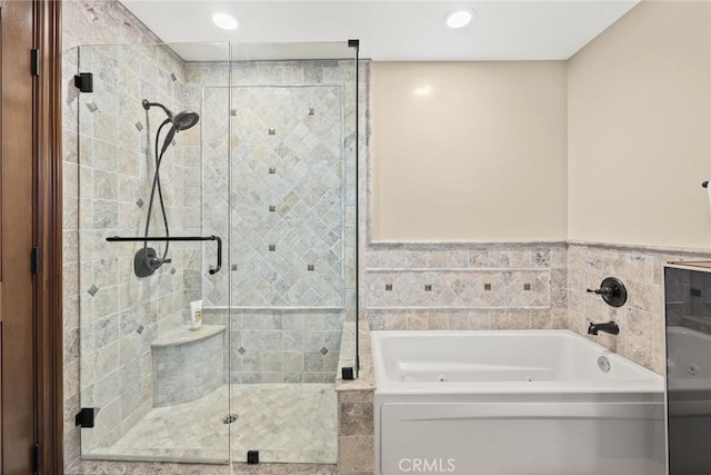 bathroom with tile walls and shower with separate bathtub