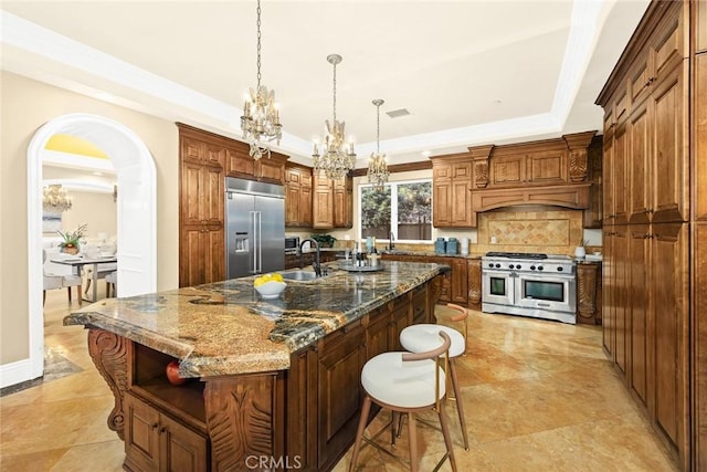 kitchen featuring pendant lighting, dark stone counters, high quality appliances, and an island with sink