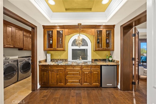 bar featuring washer and clothes dryer, a raised ceiling, light stone counters, dark hardwood / wood-style flooring, and stainless steel refrigerator