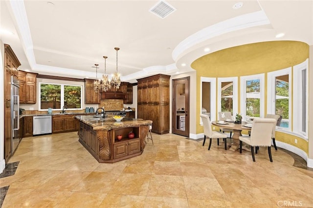 kitchen featuring dishwasher, stone counters, a center island with sink, hanging light fixtures, and a notable chandelier