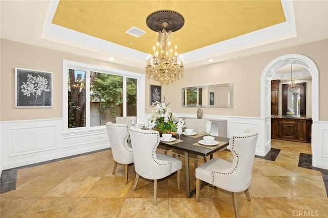 dining room with a raised ceiling and ornamental molding