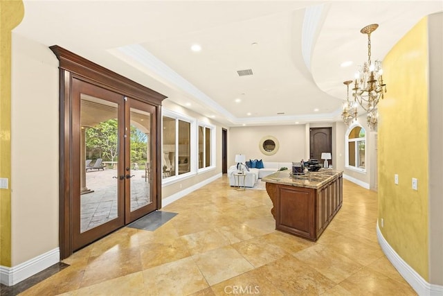 kitchen with french doors, an inviting chandelier, stone counters, a kitchen island, and hanging light fixtures