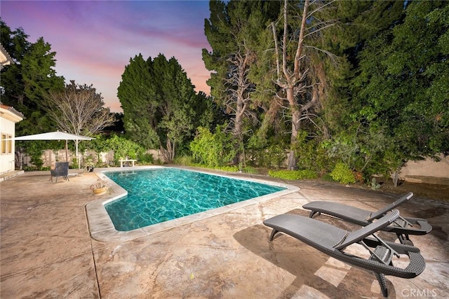 pool at dusk featuring a patio area