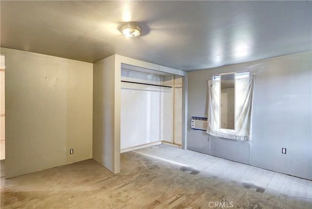 unfurnished bedroom featuring light wood-type flooring, a wall mounted air conditioner, and a closet