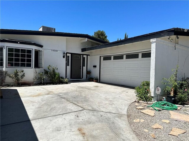 single story home with concrete driveway, an attached garage, and stucco siding