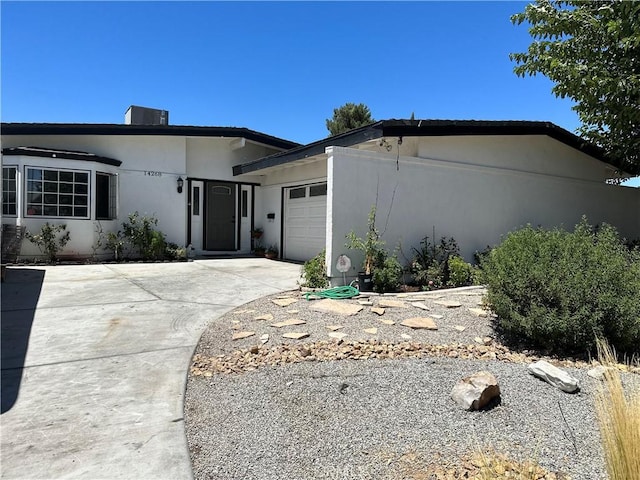 view of front of house with a garage, concrete driveway, and stucco siding