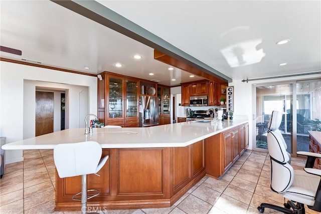 kitchen with a breakfast bar, kitchen peninsula, sink, crown molding, and stainless steel appliances