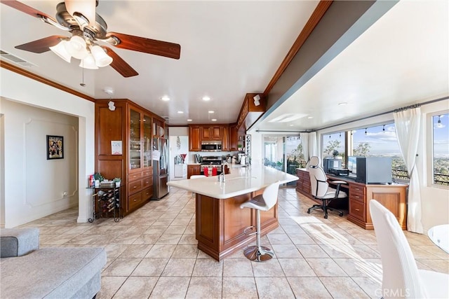 kitchen featuring appliances with stainless steel finishes, ceiling fan, a breakfast bar, light tile patterned floors, and crown molding