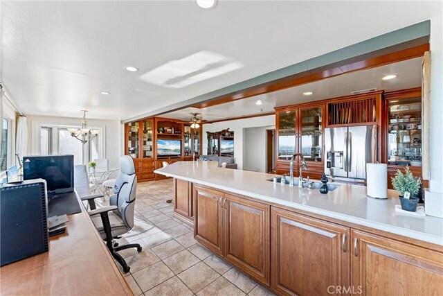 kitchen featuring stainless steel refrigerator with ice dispenser, decorative light fixtures, light tile patterned flooring, and ceiling fan with notable chandelier