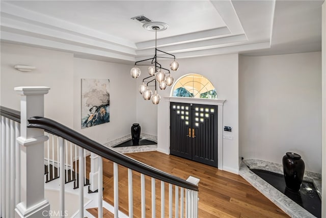 foyer with hardwood / wood-style floors, a chandelier, and a tray ceiling