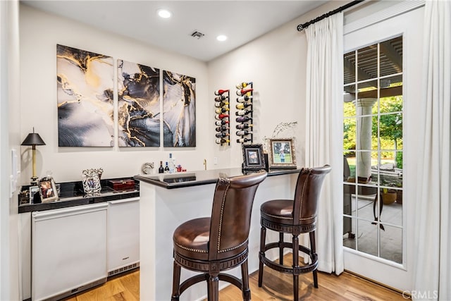 bar with light hardwood / wood-style floors and tile counters