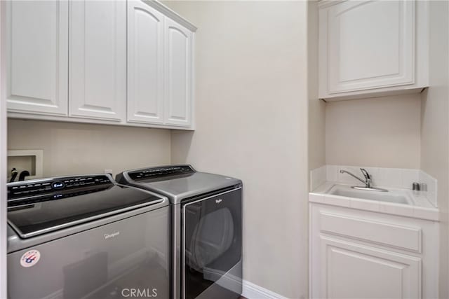 washroom with sink, washing machine and dryer, and cabinets