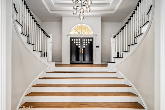 foyer entrance with a notable chandelier and a tray ceiling