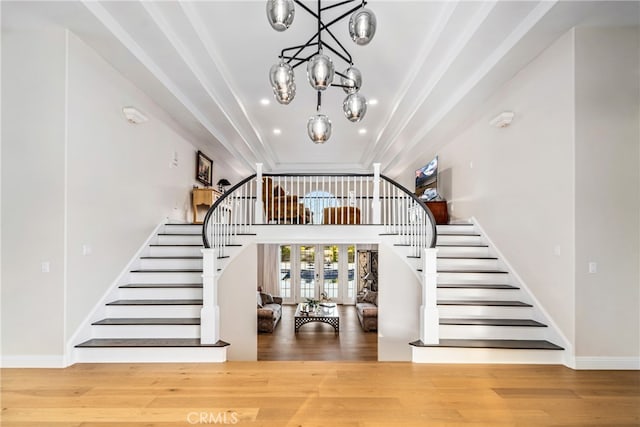 stairs featuring wood-type flooring, a notable chandelier, and a tray ceiling