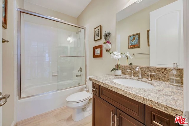 full bathroom featuring vanity with extensive cabinet space, toilet, and shower / bath combination with glass door