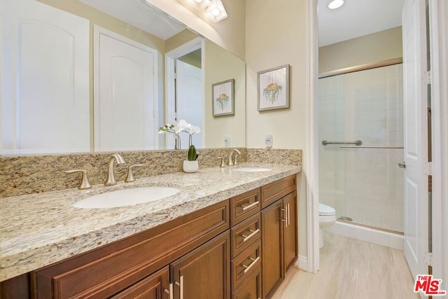 bathroom featuring dual sinks, toilet, oversized vanity, and walk in shower