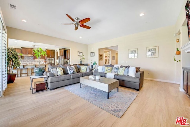 living room with light hardwood / wood-style flooring and ceiling fan