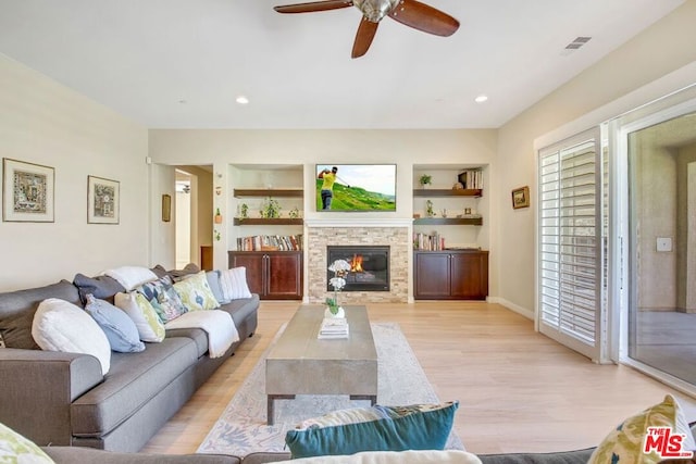 living room with light hardwood / wood-style flooring, ceiling fan, a fireplace, and built in shelves