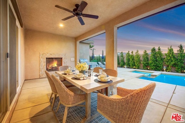 patio terrace at dusk featuring a grill, ceiling fan, and a fenced in pool