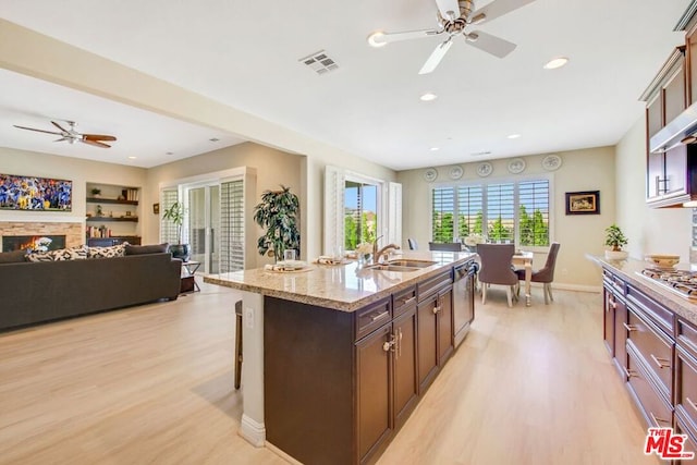 kitchen featuring light hardwood / wood-style floors, ceiling fan, sink, and a fireplace