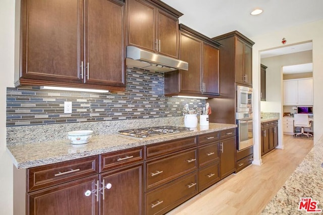 kitchen featuring light stone countertops, appliances with stainless steel finishes, light hardwood / wood-style floors, tasteful backsplash, and dark brown cabinetry