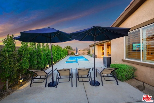 patio terrace at dusk featuring central AC unit and a fenced in pool