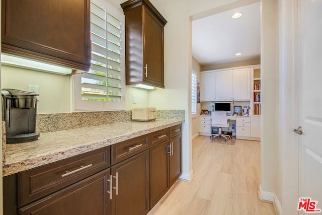 kitchen with dark brown cabinets, light hardwood / wood-style floors, and light stone countertops