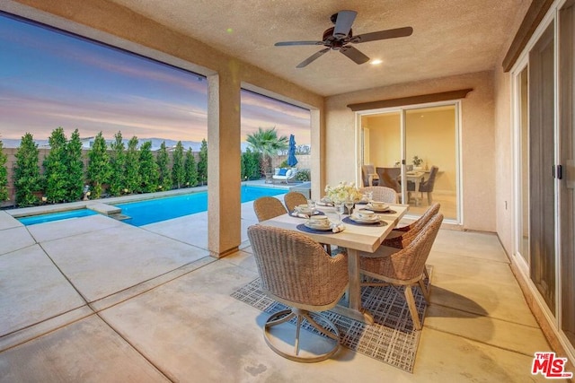 patio terrace at dusk with a fenced in pool and ceiling fan