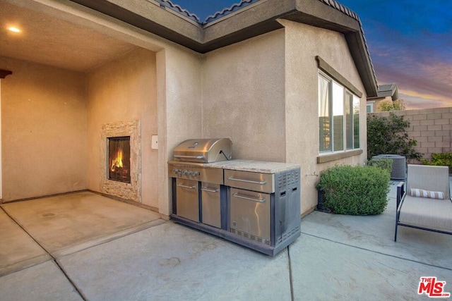 patio terrace at dusk featuring an outdoor kitchen