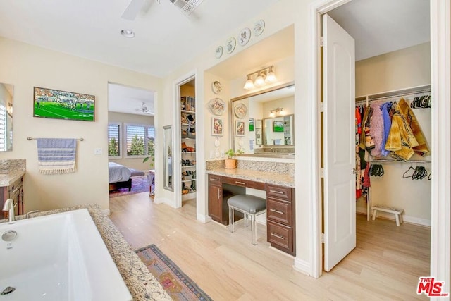 bathroom with a bath, ceiling fan, vanity, and hardwood / wood-style flooring