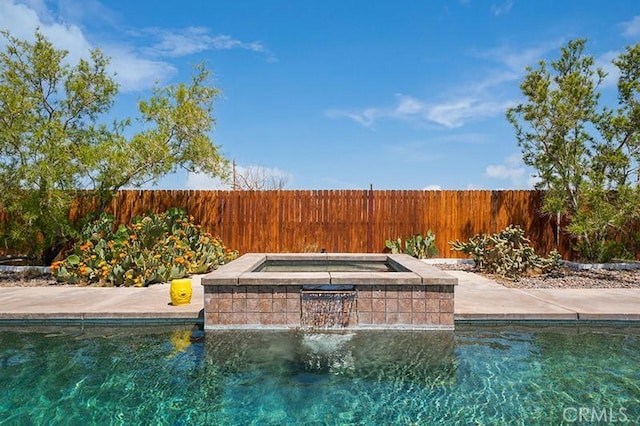 view of swimming pool with pool water feature and an in ground hot tub