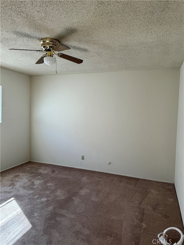 empty room featuring dark colored carpet, a textured ceiling, and ceiling fan