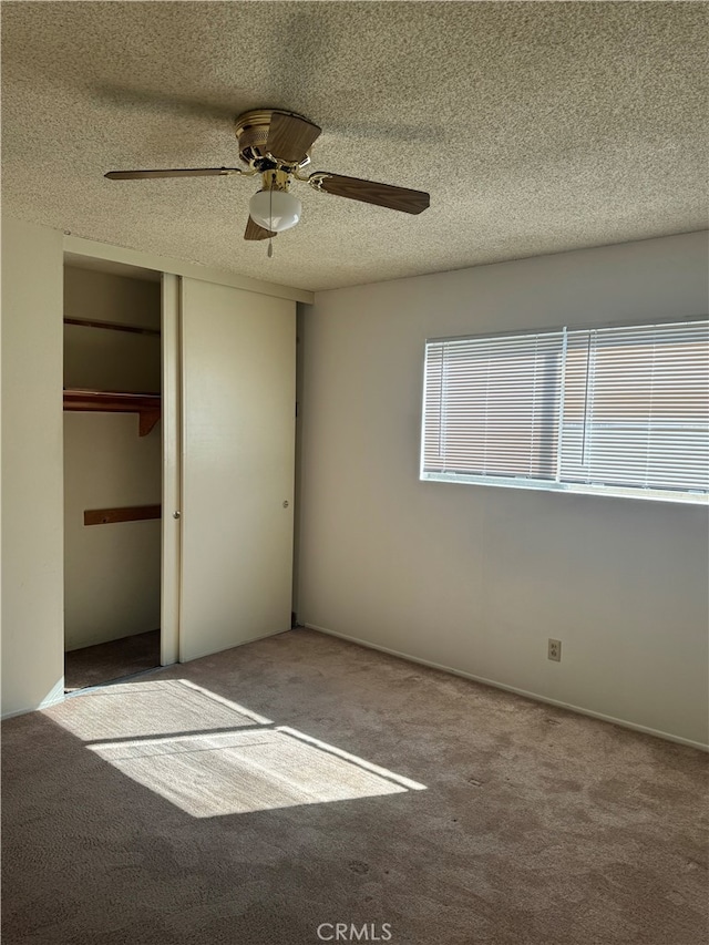 unfurnished bedroom with a textured ceiling, carpet floors, a closet, and ceiling fan