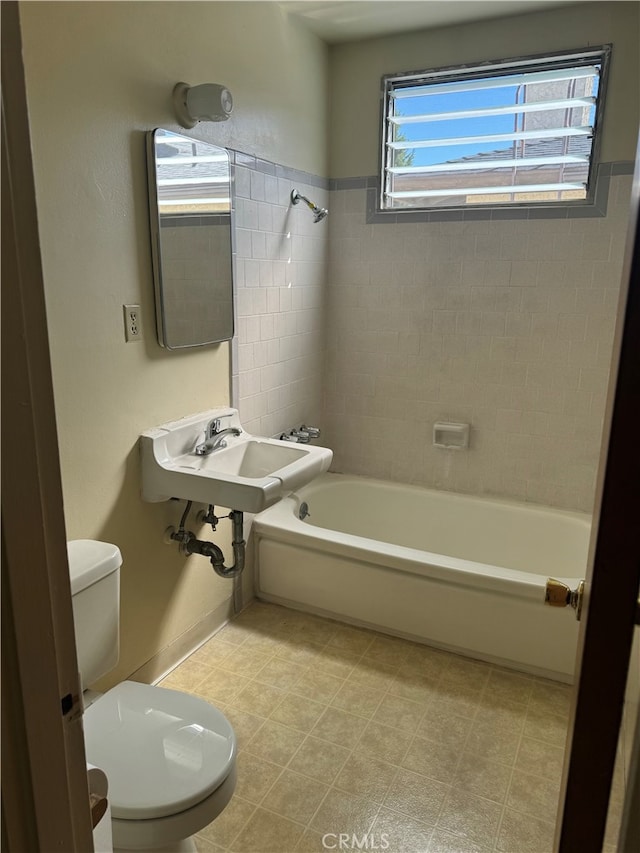 full bathroom featuring sink, tiled shower / bath, and toilet