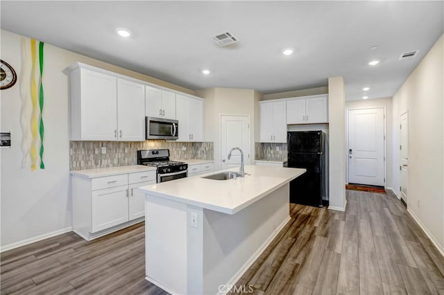 kitchen with white cabinets, appliances with stainless steel finishes, an island with sink, and sink