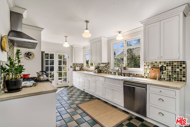 kitchen with hanging light fixtures, dark tile floors, white cabinets, and stainless steel dishwasher