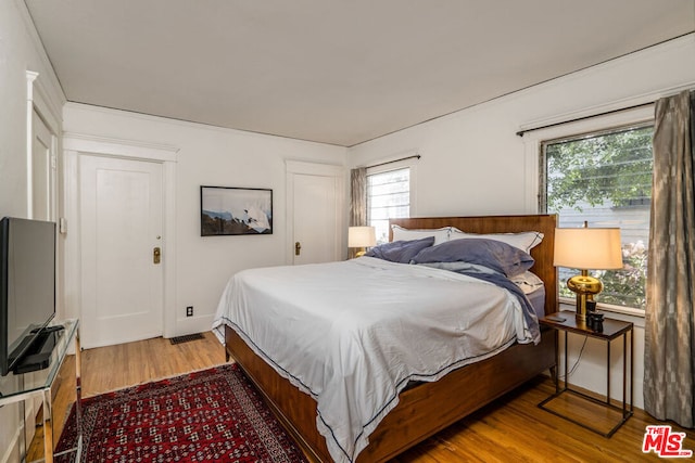 bedroom with light hardwood / wood-style floors and multiple windows