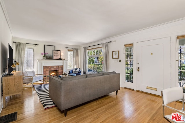 living room with ornamental molding, light hardwood / wood-style flooring, and a tile fireplace