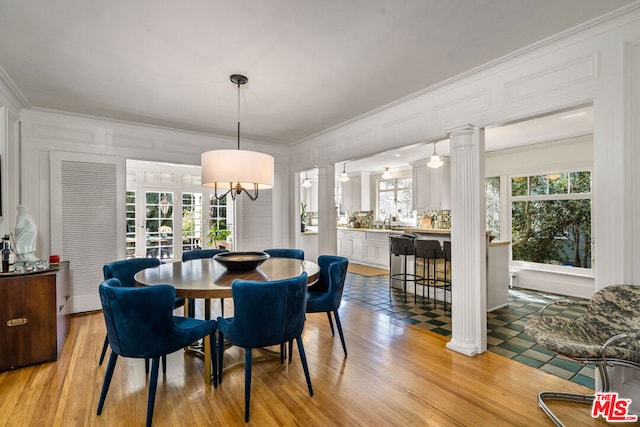 tiled dining area with plenty of natural light, crown molding, and decorative columns