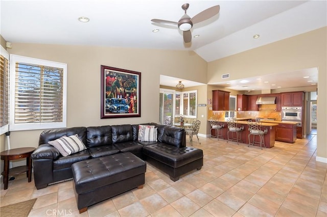 living room featuring ceiling fan, light tile patterned floors, and vaulted ceiling