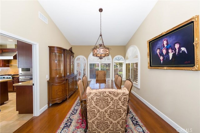 dining area with light wood-type flooring and vaulted ceiling