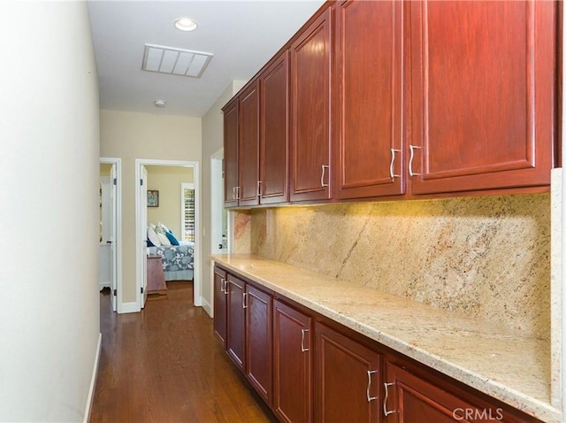 kitchen featuring tasteful backsplash, light stone countertops, and dark hardwood / wood-style flooring