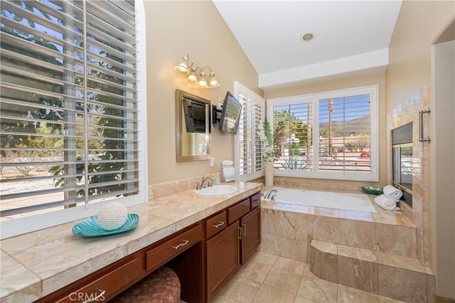 bathroom featuring tiled bath, tile patterned flooring, vanity, and vaulted ceiling