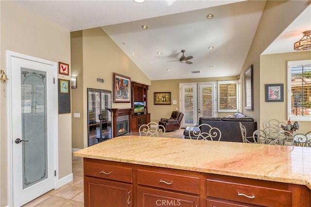 kitchen featuring french doors, light stone counters, ceiling fan, light tile patterned floors, and lofted ceiling