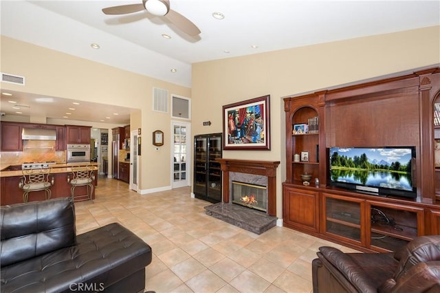 tiled living room with ceiling fan, a high end fireplace, and vaulted ceiling