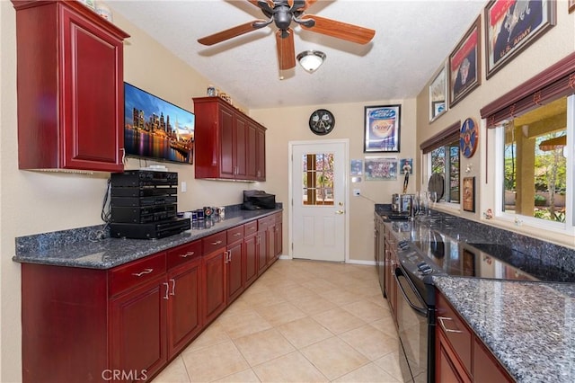 kitchen featuring ceiling fan, dark stone countertops, light tile patterned floors, and range with electric cooktop