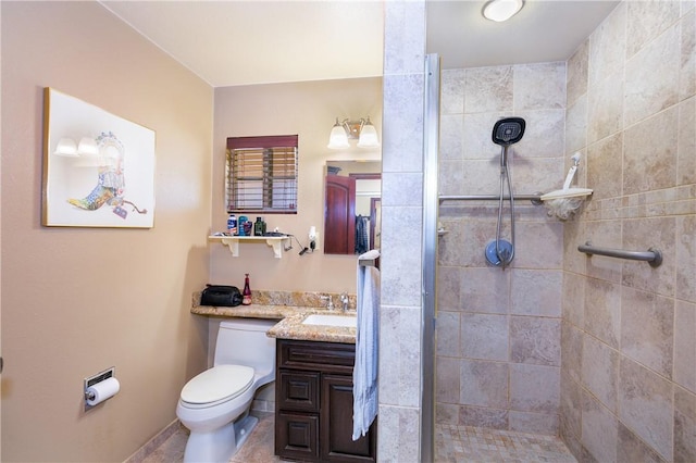 bathroom with tiled shower, vanity, and toilet