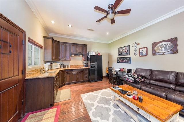 kitchen with black fridge with ice dispenser, light wood-type flooring, ornamental molding, and dark brown cabinetry