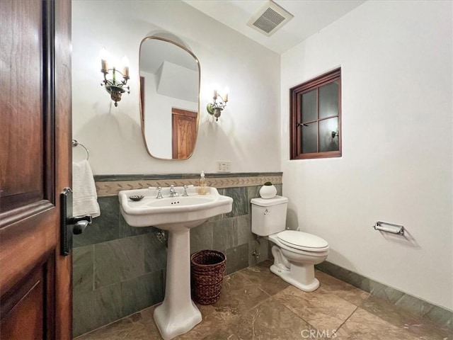 bathroom featuring toilet and tile walls