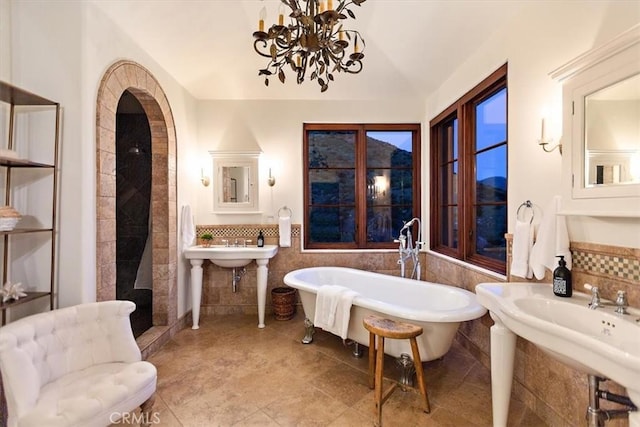 bathroom featuring vaulted ceiling, sink, a bath, a notable chandelier, and tile patterned flooring